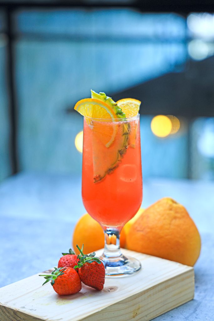 A glass of ice-cold strawberry, orange, and pineapple drink